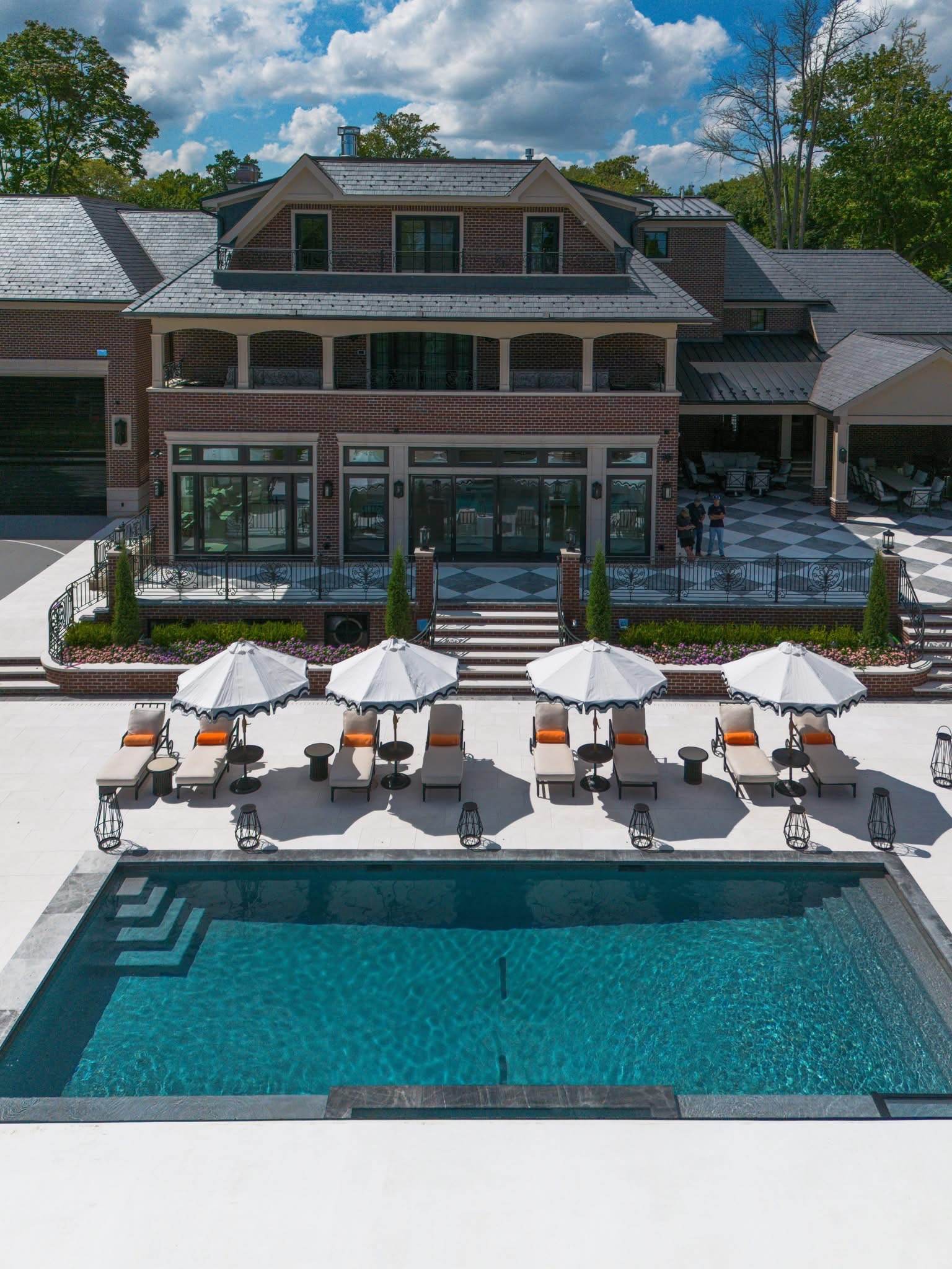 Luxury inground pool with marble deck, poolside umbrellas and lounge chairs at a Pool Doctor estate project