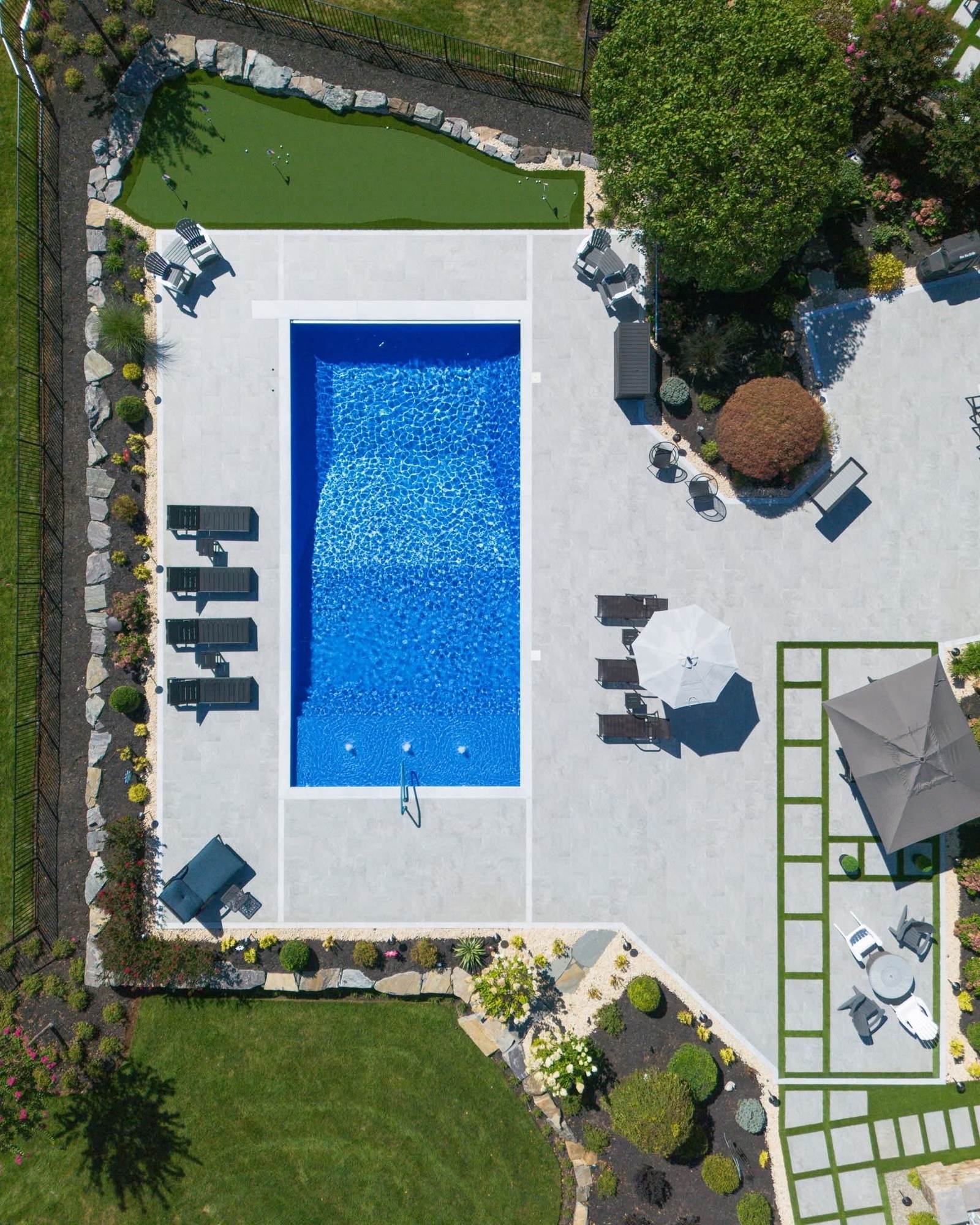 Aerial view of a custom inground pool, stone patio and outdoor dining area