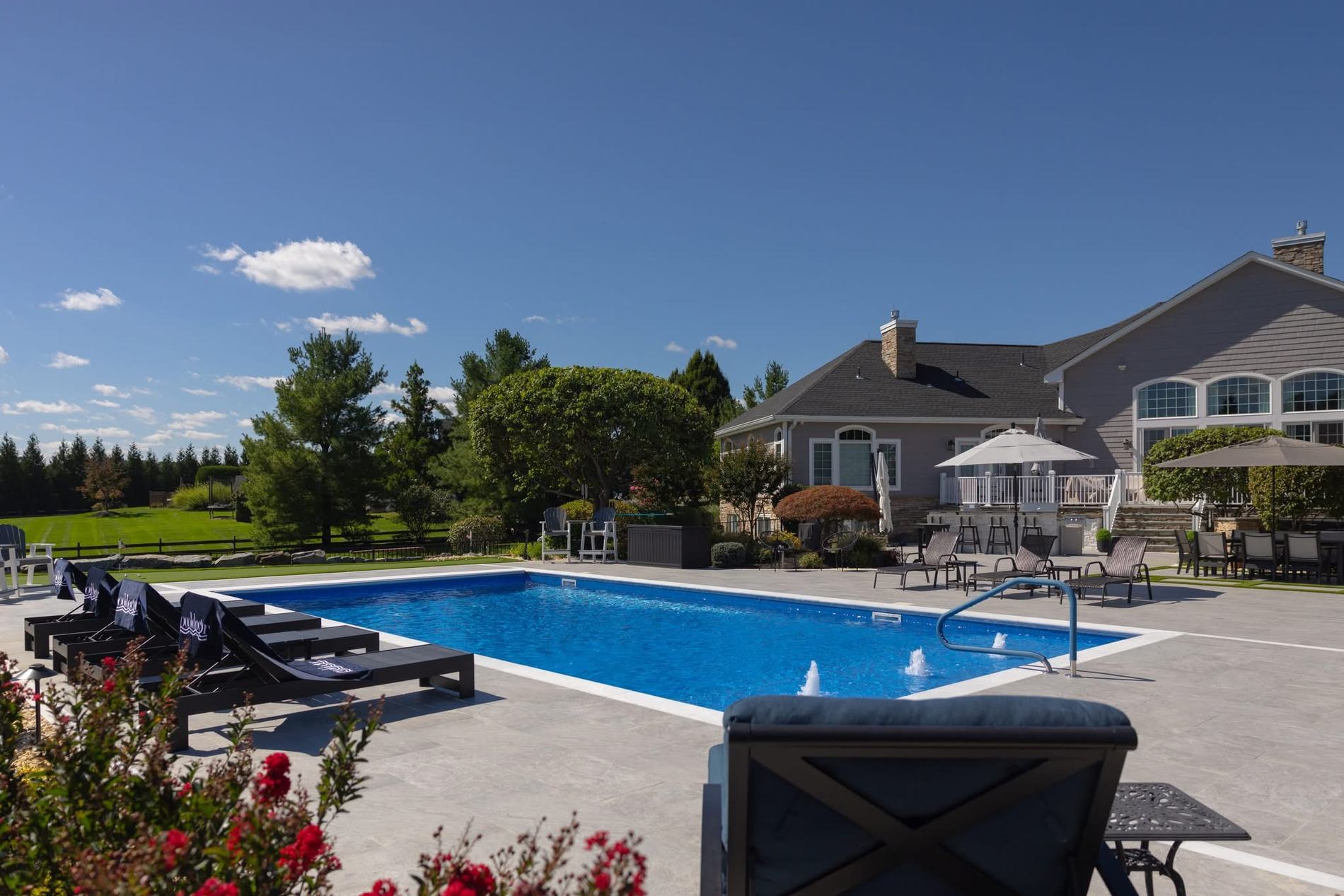 Resort-style backyard with custom inground pool, stone patio, outdoor bar and lounge seating