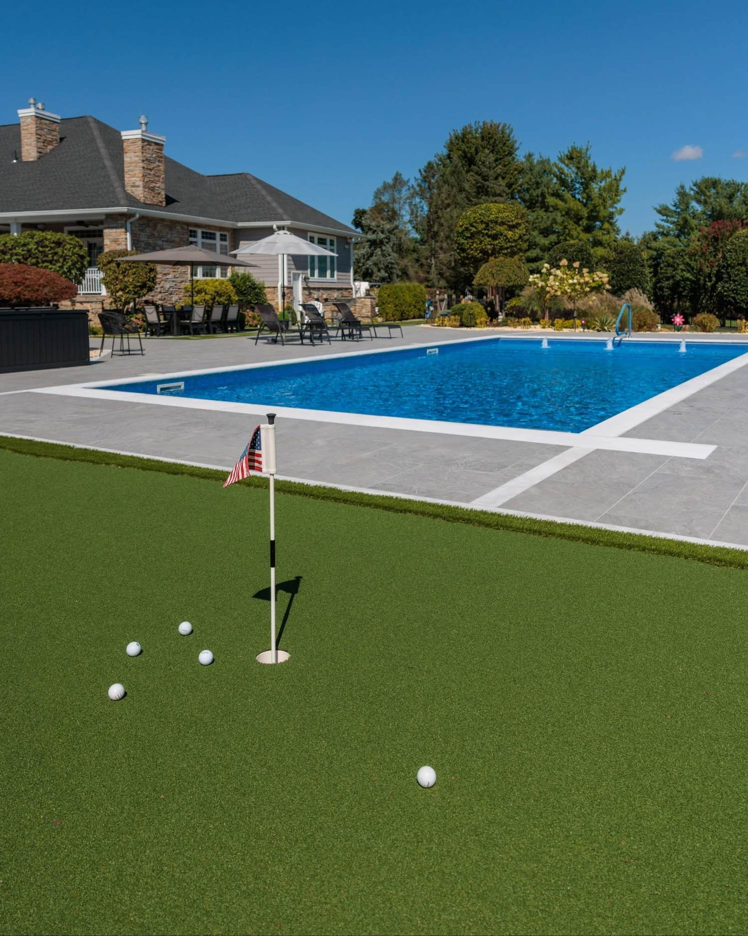 Custom inground pool with adjoining putting green and stone patio