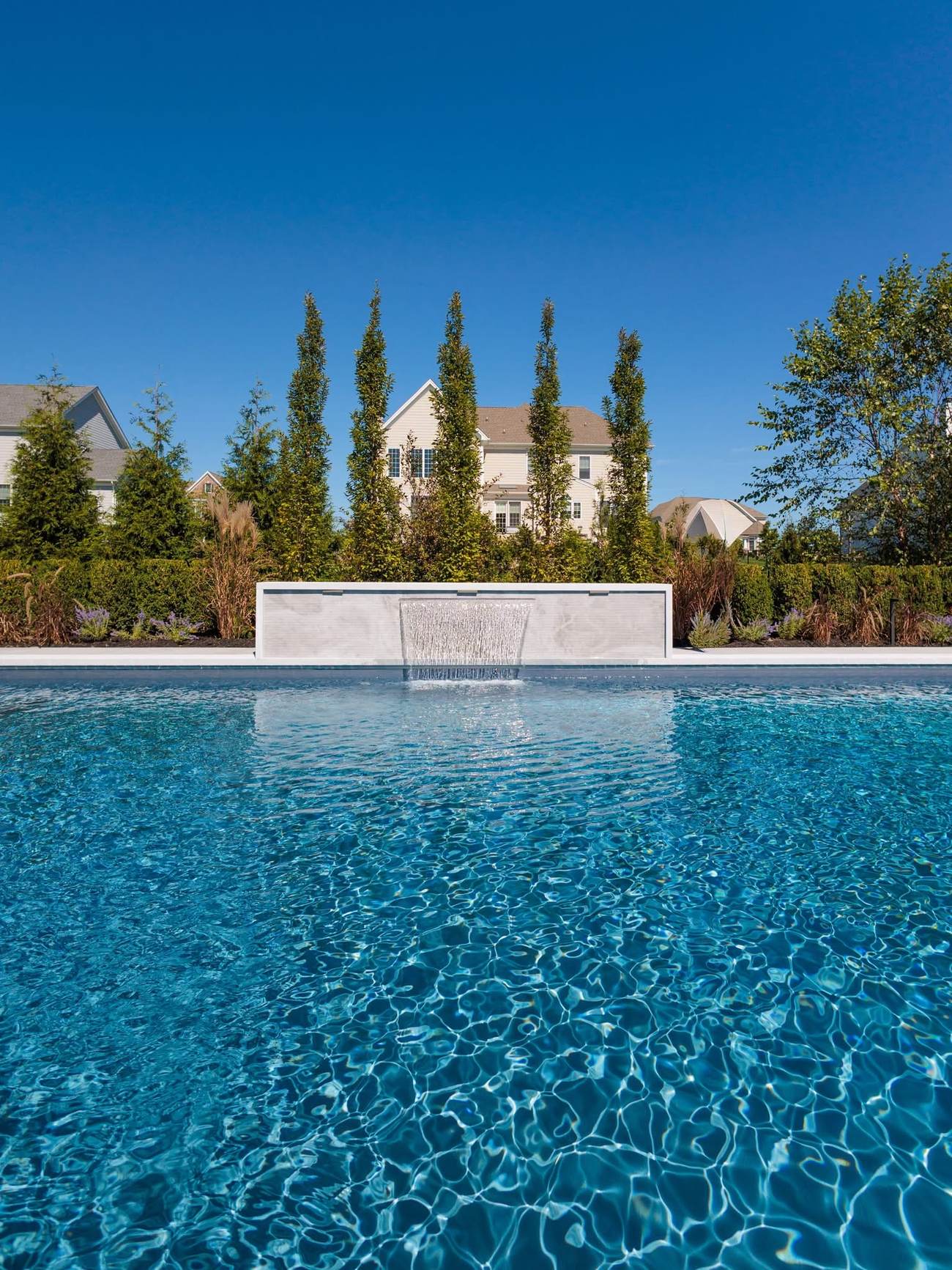 Close view of a sheer descent water feature flowing into a custom pool
