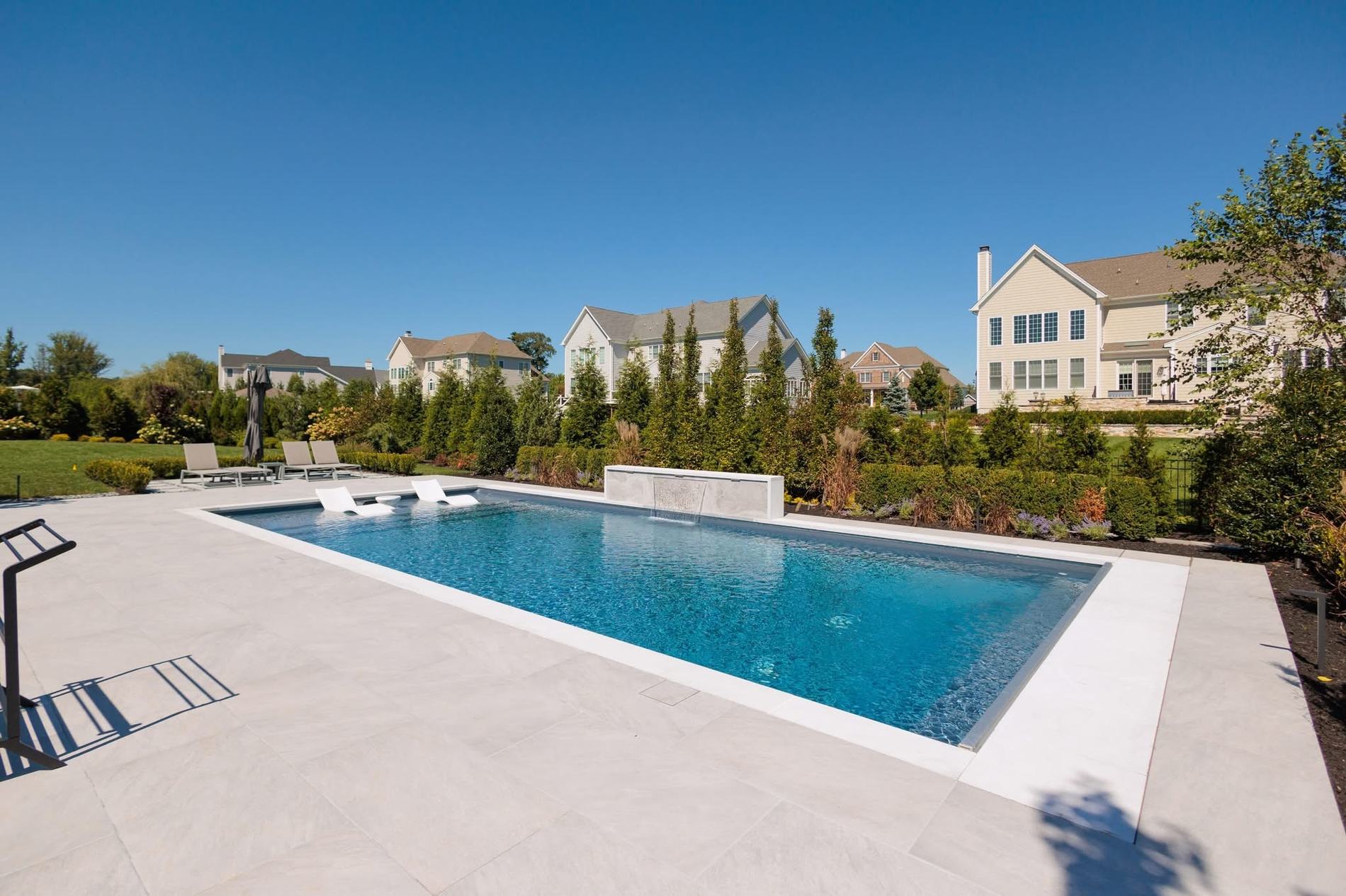 Modern inground pool with a raised sheer-descent water feature wall