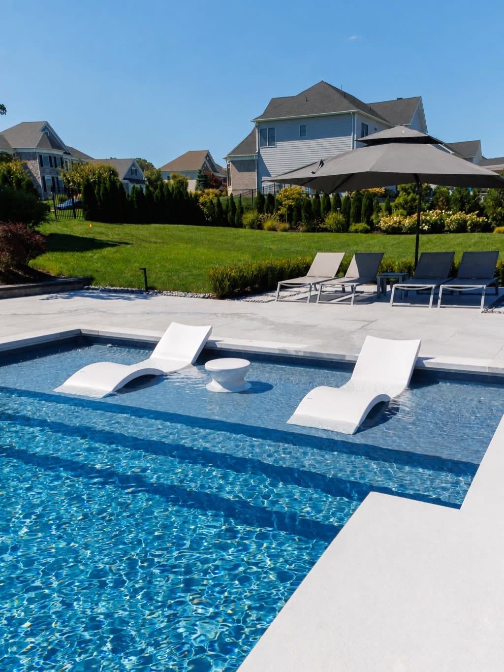 In-pool tanning ledge with two submerged lounge chairs and a side table
