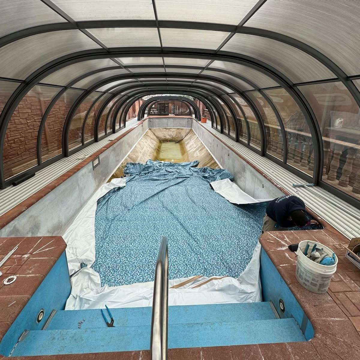 Enclosed lap pool with new vinyl liner being installed, liner draped and not yet fitted